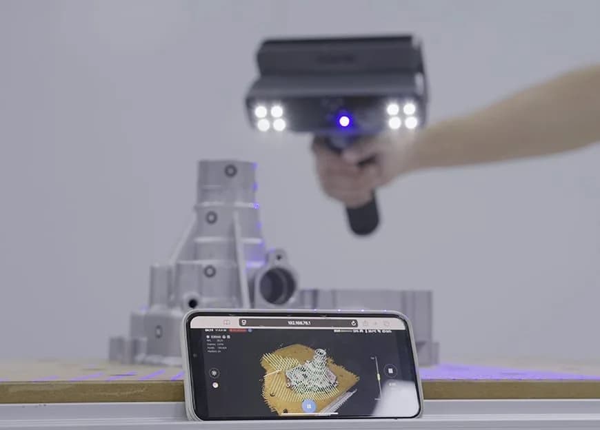 EinScan Rigil scanner over a housing casting, with a point-cloud display in front of it
