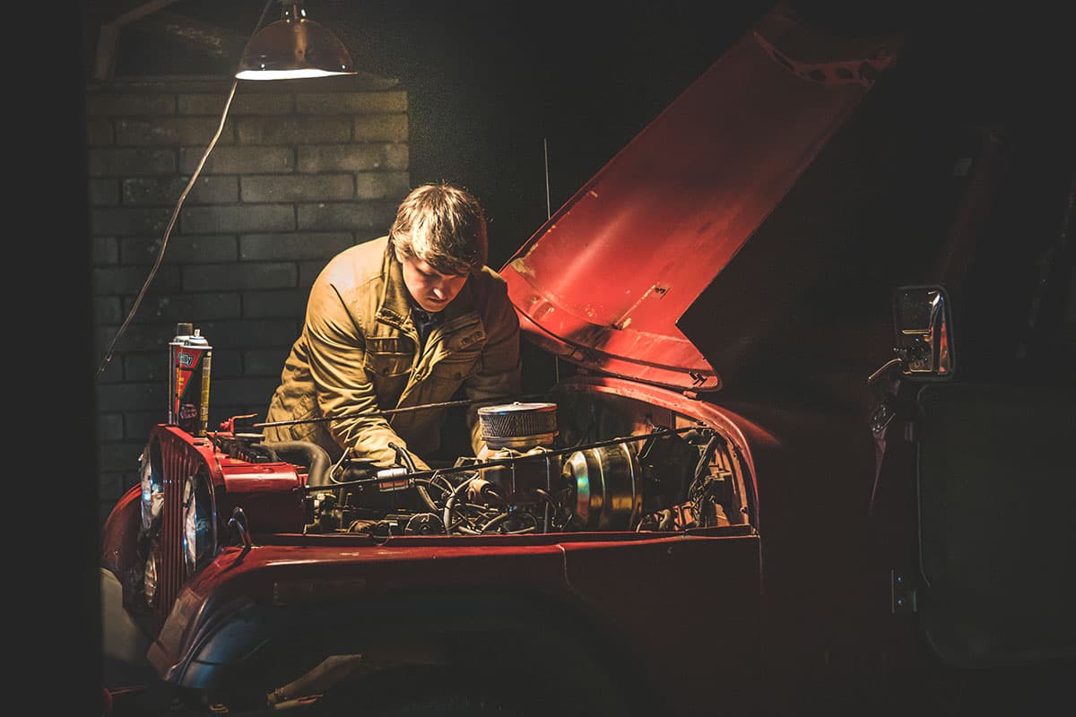 Mechanic working under the bonnet of a classic car