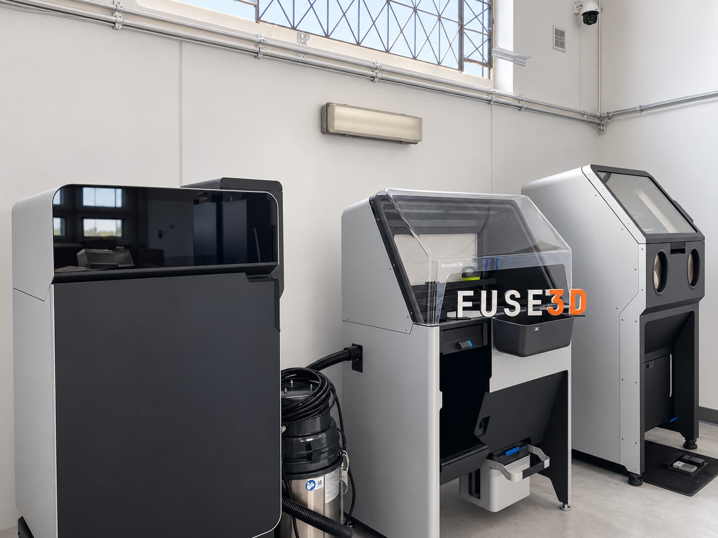 A side view of the SLS workstation with the printer, vacuum, powder recovery and part cleaning equipment.