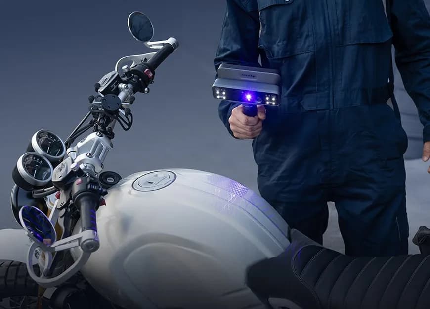Operator holding an EinScan Rigil scanner over a motorcycle fuel tank.